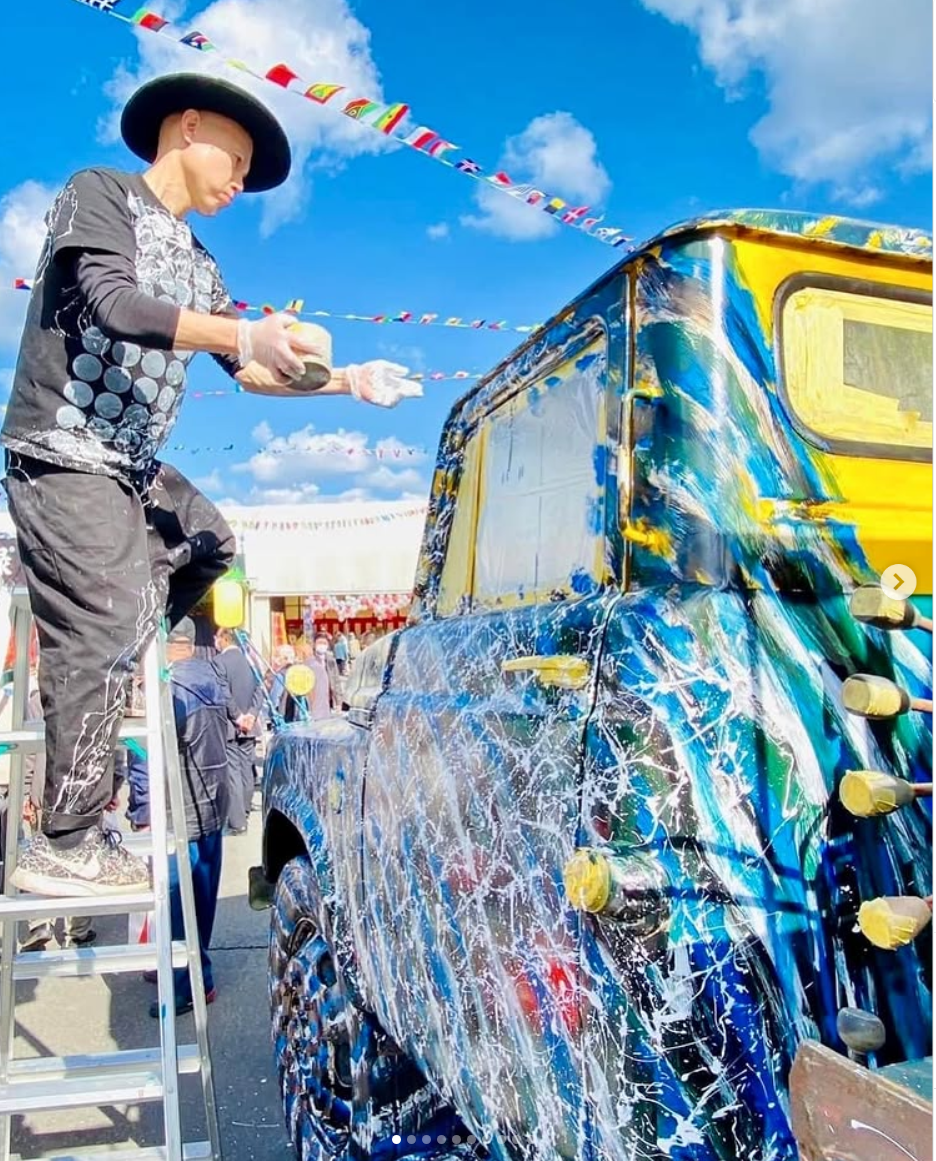 青空の下、車にシブキを施すShibuki Takakura